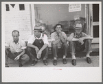 Men sitting along sidewalk in farm marketing section of Muskogee, Oklahoma