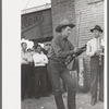 Member of orchestra which plays outside grocery store on Saturday afternoon tuning his violin, Phoenix, Arizona