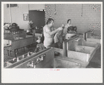Wives of migratory workers in the laundry room at the Agua Fria Migratory Labor Camp, Arizona. Hot and cold water are furnished by the camp, soap and other washing materials by the people