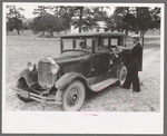 Mr. Bill Stagg putting container of food which was left from dinner at the community sing back into the car, Pie Town, New Mexico