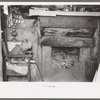 Mr. Leatherman's son reading in front of fireplace in dugout, Pie Town, New Mexico