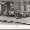 Crowd of men sitting on board walk in front of bar at Mogollon, New Mexico, gold mining town