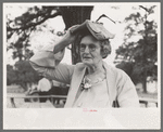 Farm woman using songbook as sunshade during dinner at all day community sing, Pie Town, New Mexico