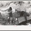 Tie workers driving steel wedges into a pine log to split it, Pie Town, New Mexico