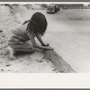 Spanish-American girl plastering edge of roof of adobe house, Costilla, New Mexico