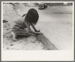 Spanish-American girl plastering edge of roof of adobe house, Costilla, New Mexico