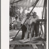 Power for the old-fashioned merry-go-round is furnished by two husky Spanish-American men, Taos, New Mexico