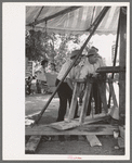 Power for the old-fashioned merry-go-round is furnished by two husky Spanish-American men, Taos, New Mexico