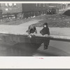 Children playing in water backed up in gutter, South Side of Chicago, Illinois