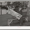 Resident of Funkley, Minnesota, reading newspaper in general store