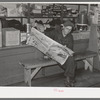 Resident of Funkley, Minnesota, reading newspaper in general store