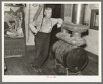 J. A. Fisher, storekeeper, postmaster and depot agent of Funkley, Minnesota, by stove of his own creation.  Funkley is rapidly becoming a "ghost town."