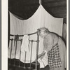 Aged Cajun woman tucking in mosquito bar under mattress. Near Crowley, Louisiana