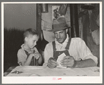 Day laborer with son playing penny-ante poker. He is a worker in the cane fields near New Iberia, Louisiana