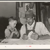 Day laborer with son playing penny-ante poker. He is a worker in the cane fields near New Iberia, Louisiana