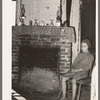 Daughter of Cajun day laborers sitting in front of fireplace in home near New Iberia, Louisiana