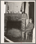 Daughter of Cajun day laborers sitting in front of fireplace in home near New Iberia, Louisiana
