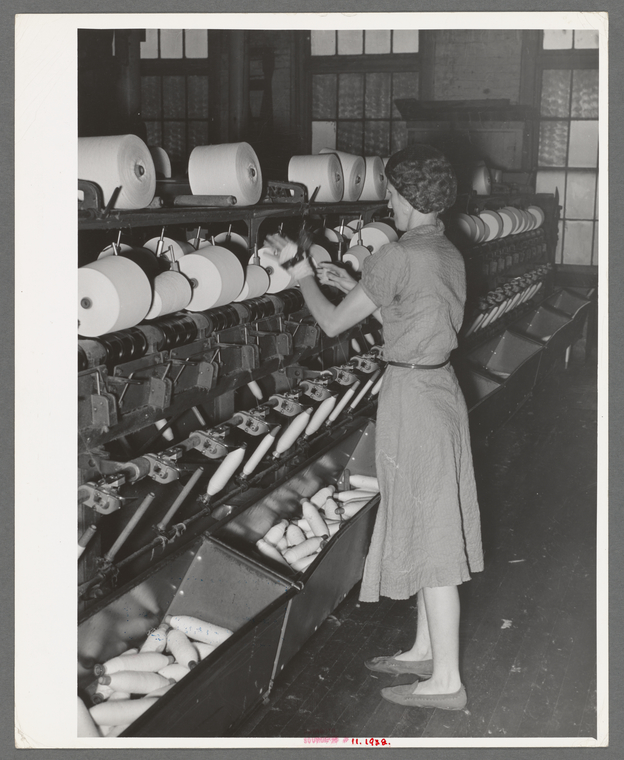 Worker winding cotton thread onto large spools.