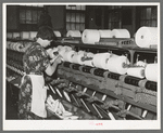 Worker winding cotton thread onto large spools. Laurel cotton mills, Laurel, Mississippi