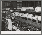 Worker winding cotton thread onto large spools. Laurel cotton mills, Laurel, Mississippi