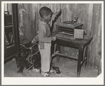 Negro child playing phonograph in cabin home. Transylvania Project, Louisiana