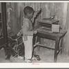 Negro child playing phonograph in cabin home. Transylvania Project, Louisiana