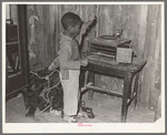 Negro child playing phonograph in cabin home. Transylvania Project, Louisiana