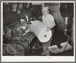 Operator removing bat of cotton from machine. First step of cleaning cotton of trash. Laurel cotton mills, Laurel, Mississippi