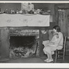 Mrs. Bagget and two children in front of fireplace. Note the board window. Laurel, Mississippi