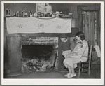 Mrs. Bagget and two children in front of fireplace. Note the board window. Laurel, Mississippi