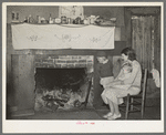 Mrs. Bagget and two children in front of fireplace. Note the board window. Laurel, Mississippi