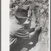 Prospector taking a sample of dirt from creek bed which contains scattered gold, Pinos Altos, New Mexico