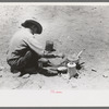 Faro Caudill frying eggs over camp fire the day he was moving his dugout, Pie Town, New Mexico