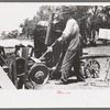 Farmer drilling water well. In this picture he is loosening and tightening rope around the pulley, thus raising and lowering the drilling tool, Pie Town, New Mexico