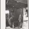 Jack Whinery's daughter washing her hands. This picture was taken in the dugout with natural lighting. Notice the water cooler in cooling room at right. This cooling room is built cellar-like into the ground, Pie Town, New Mexico