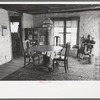 Wife of homesteader working in dining room of her new adobe house. The lamp-chandelier above dining table was brought by her grandmother to Iowa when she homesteaded there, Pie Town, New Mexico