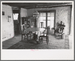 Wife of homesteader working in dining room of her new adobe house. The lamp-chandelier above dining table was brought by her grandmother to Iowa when she homesteaded there, Pie Town, New Mexico