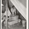 Migrant white mother washing clothes in front of tent home. Weslaco, Texas