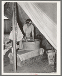 Migrant white mother washing clothes in front of tent home. Weslaco, Texas