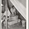 Migrant white mother washing clothes in front of tent home. Weslaco, Texas