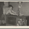 Son of migrant worker reaching for lamp atop cabinet in trailer home. Weslaco, Texas