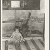 Child of migrant parents sitting on drop bed in trailer home. Weslaco, Texas