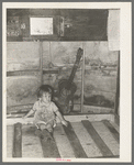 Child of migrant parents sitting on drop bed in trailer home. Weslaco, Texas