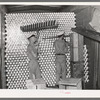 Unloading cans from a boxcar is done by picking them up on a row of spikes placed on a T. Cans go directly to the sterilizer and canning machine. Grapefruit juice canning plant, Weslaco, Texas
