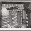 Unloading cans from a boxcar is done by picking them up on a row of spikes placed on a T. Cans go directly to the sterilizer and canning machine. Grapefruit juice canning plant, Weslaco, Texas