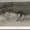 Child migrant with doll in tent home. Harlingen, Texas