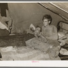 White migrant worker lying on bed in tent home near Mercedes, Texas