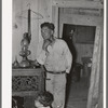 Spanish-American and child inside shack. Labor contractor. Notice that the doorway shows the construction of the house. Two houses have been joined together. Robstown, Texas