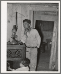 Spanish-American and child inside shack. Labor contractor. Notice that the doorway shows the construction of the house. Two houses have been joined together. Robstown, Texas