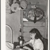 Mexican girl sewing in their home. Robstown, Texas. Contrary to the prevalent idea, Mexicans generally are extremely neat and clean even when they live in most crowded conditions